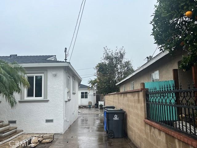 view of side of property featuring stucco siding, fence, roof with shingles, and crawl space