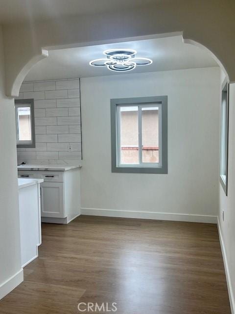 interior space featuring wood finished floors, baseboards, and arched walkways