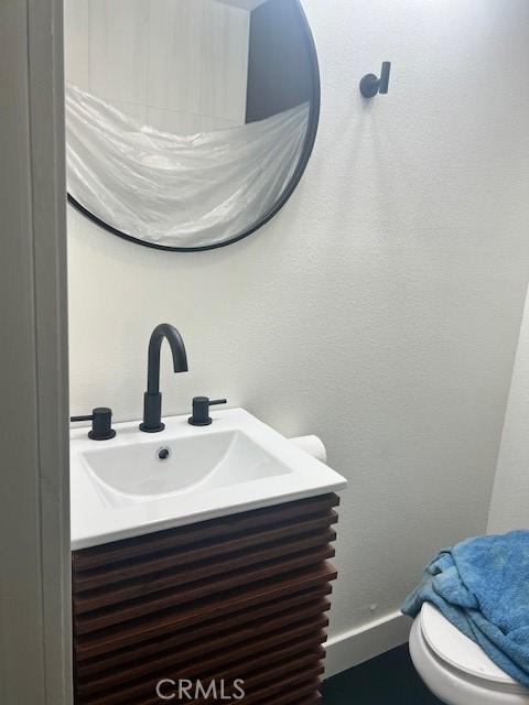 bathroom with vanity, a textured wall, and baseboards