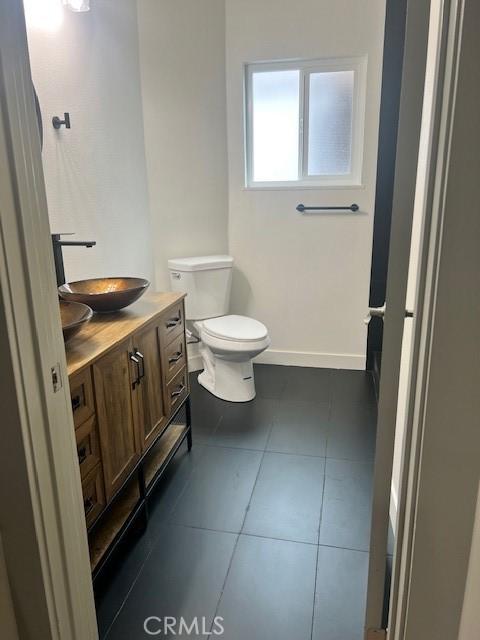 bathroom with tile patterned floors, baseboards, toilet, and vanity