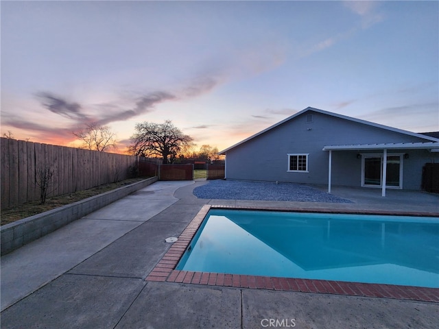 pool at dusk with a fenced in pool, a patio, and a fenced backyard