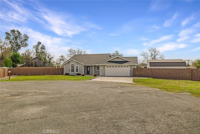 view of front of property with a front lawn, an attached garage, fence, and driveway