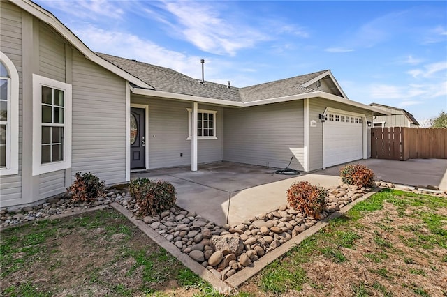 exterior space featuring concrete driveway, an attached garage, fence, and a patio area