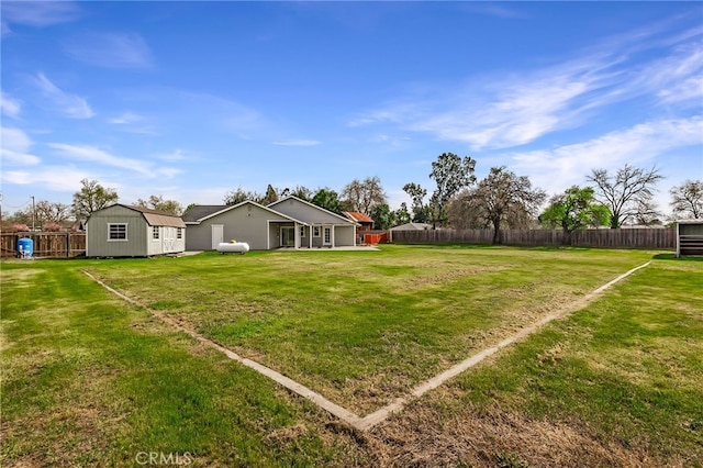 view of yard with an outdoor structure, a fenced backyard, and a shed