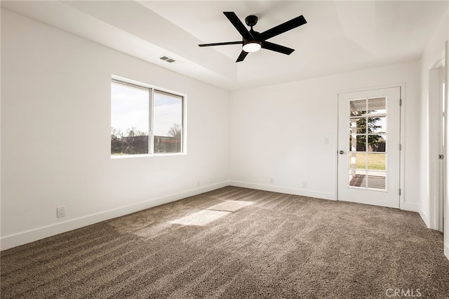 carpeted spare room featuring a ceiling fan, a raised ceiling, baseboards, and visible vents