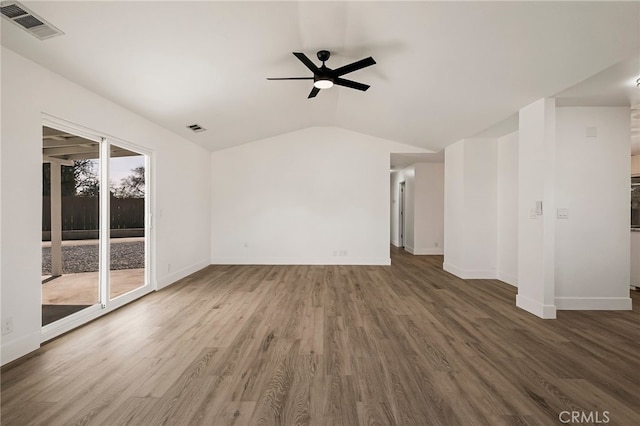 empty room featuring a ceiling fan, vaulted ceiling, wood finished floors, and visible vents