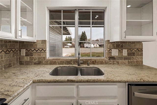 kitchen featuring backsplash, white cabinetry, glass insert cabinets, and a sink