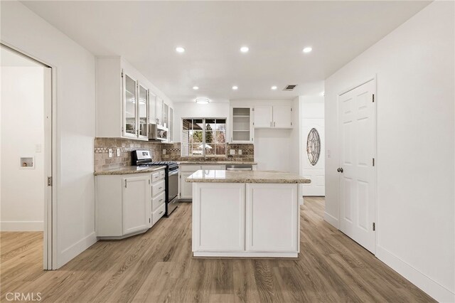 kitchen featuring tasteful backsplash, white cabinets, stainless steel appliances, and light wood-type flooring