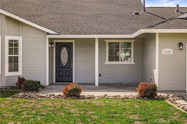 view of exterior entry with a shingled roof