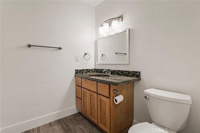 half bath featuring vanity, toilet, and baseboards