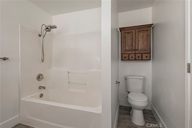 bathroom featuring toilet, shower / bath combination, baseboards, and wood finished floors