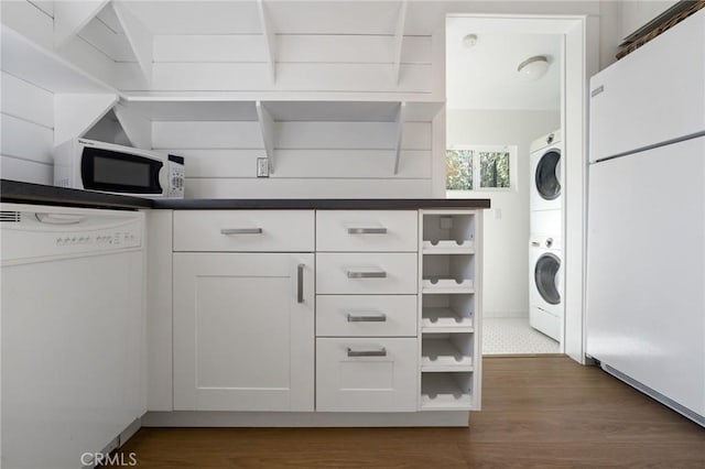 laundry area featuring dark wood finished floors, laundry area, and stacked washer and dryer