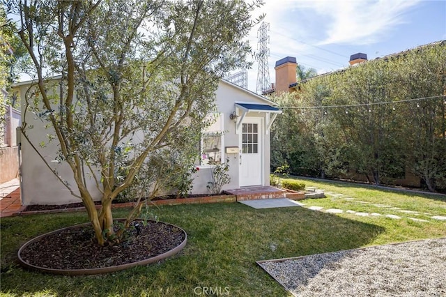 exterior space featuring stucco siding and a lawn