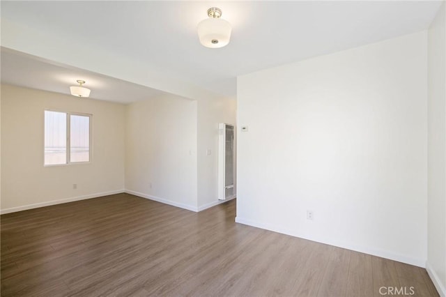 empty room with baseboards and wood finished floors