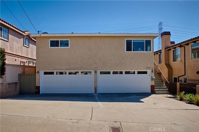 view of front of house with stairs, concrete driveway, a garage, and stucco siding