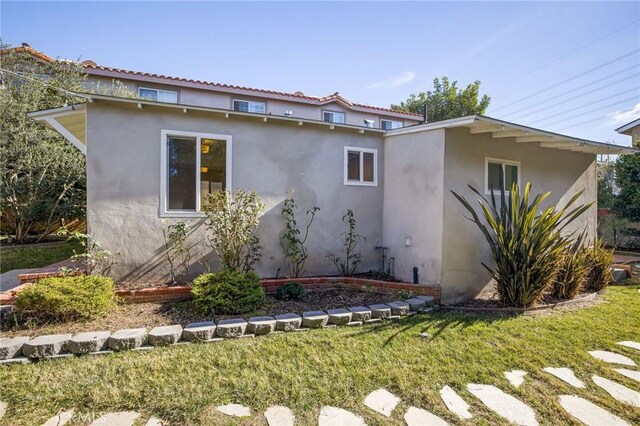 view of side of home featuring stucco siding and a lawn