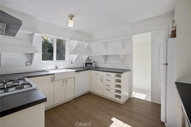 kitchen with open shelves, white appliances, dark countertops, and wood finished floors