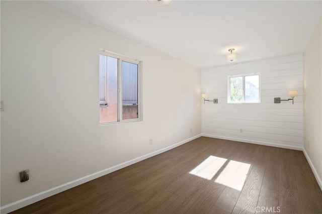 spare room with baseboards and wood finished floors