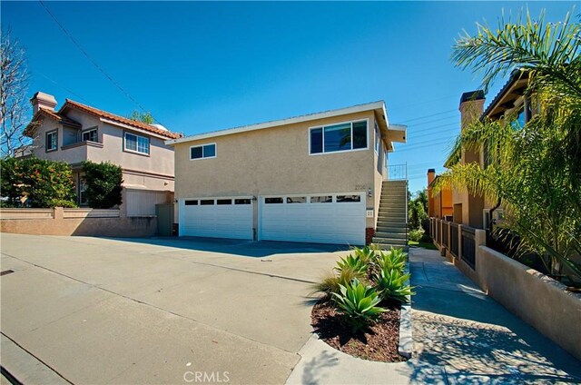 view of front facade featuring stairway, fence, driveway, an attached garage, and stucco siding