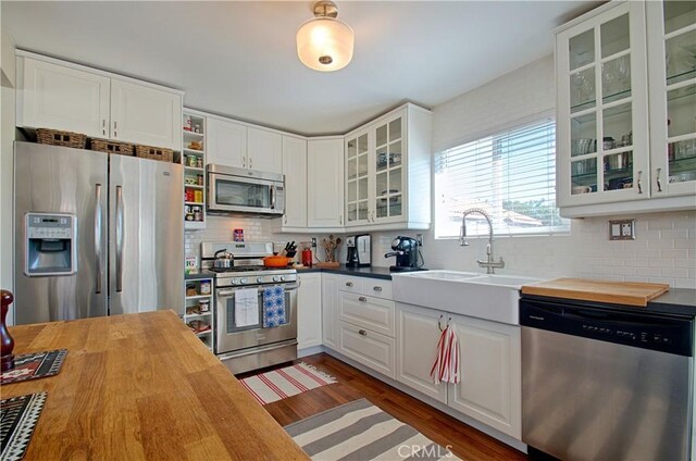 kitchen with a sink, stainless steel appliances, wood finished floors, and wood counters