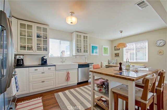 kitchen with wood finished floors, visible vents, a sink, appliances with stainless steel finishes, and tasteful backsplash