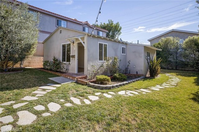 exterior space with stucco siding and a front yard