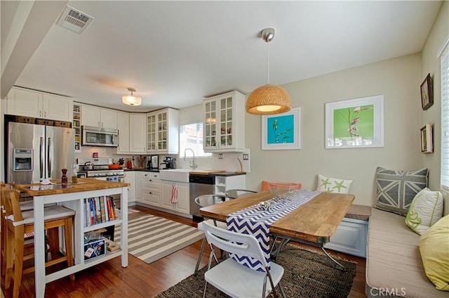 kitchen with visible vents, a sink, tasteful backsplash, appliances with stainless steel finishes, and dark wood-style flooring