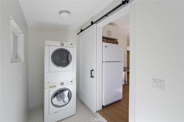 clothes washing area with stacked washer and clothes dryer and a barn door