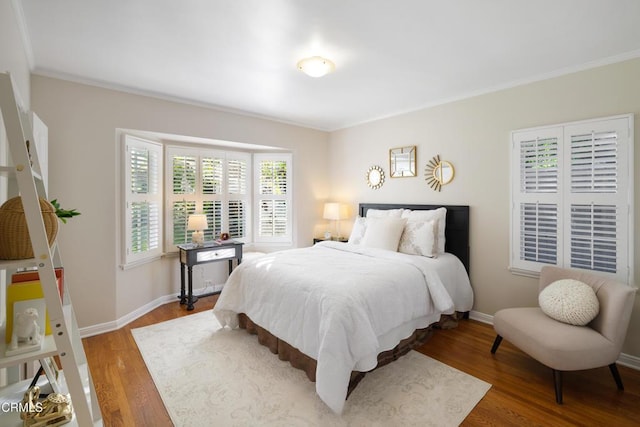 bedroom with crown molding, baseboards, and wood finished floors