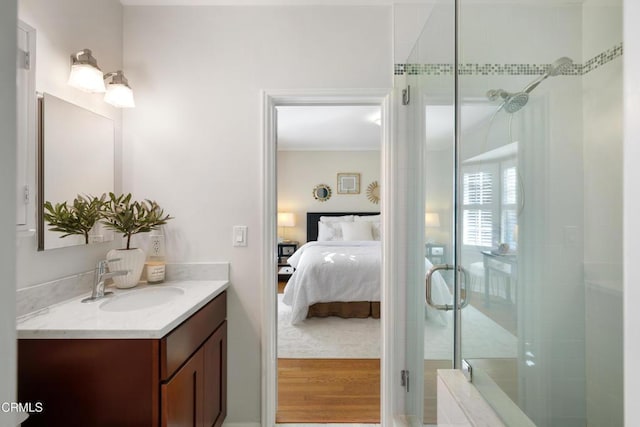 ensuite bathroom featuring connected bathroom, vanity, wood finished floors, and a shower stall