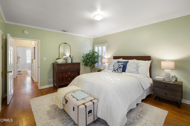 bedroom with baseboards, multiple windows, and wood finished floors