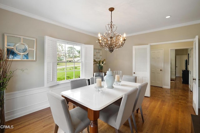 dining room with a chandelier, wainscoting, wood finished floors, and crown molding