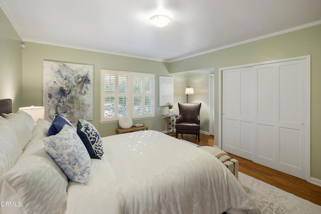 bedroom with a closet, ornamental molding, baseboards, and wood finished floors