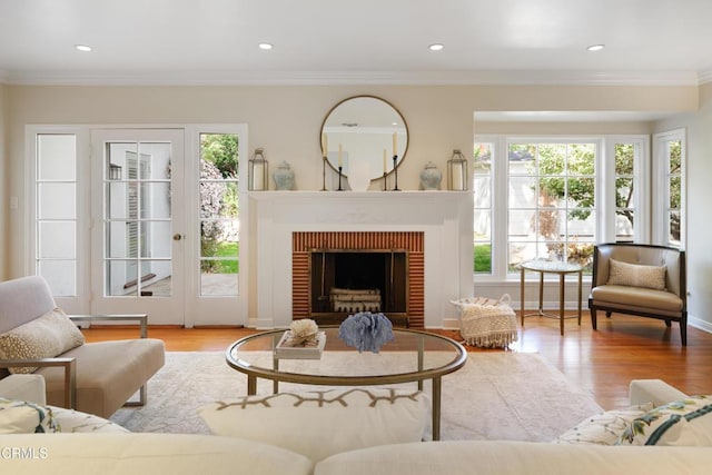 living room featuring a brick fireplace, wood finished floors, and ornamental molding