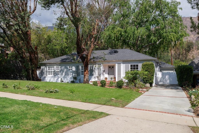 ranch-style house featuring a front lawn, a gate, and driveway