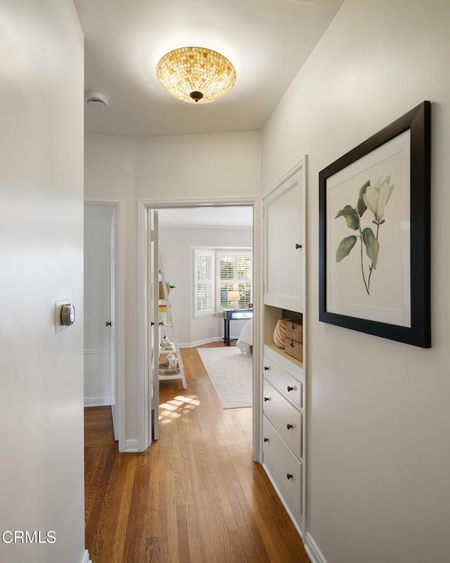 corridor featuring baseboards and wood finished floors