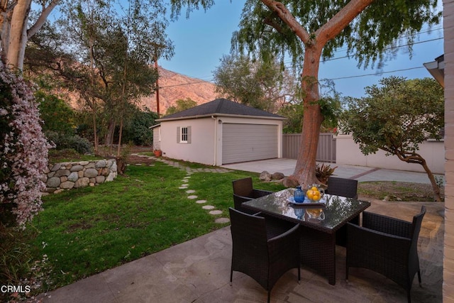 view of patio featuring an outbuilding, outdoor dining area, a detached garage, and fence