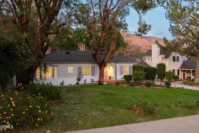 view of front of home featuring a front yard, a mountain view, and stucco siding