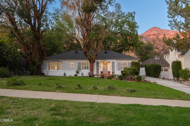 single story home featuring a front lawn, a mountain view, and stucco siding