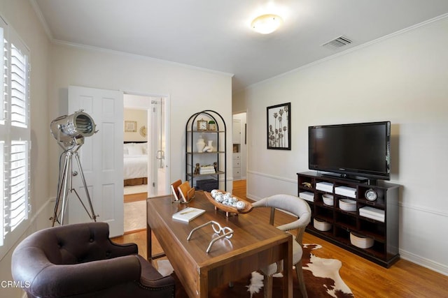 interior space with ornamental molding, baseboards, visible vents, and light wood-type flooring