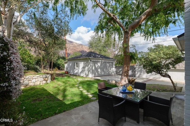 view of yard with a patio area, outdoor dining space, an outdoor structure, and fence