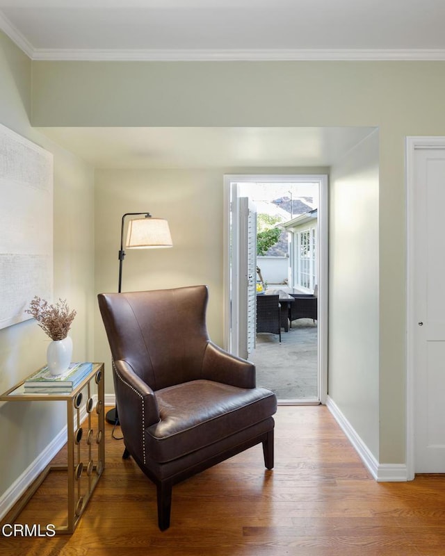 sitting room with ornamental molding, baseboards, and wood finished floors