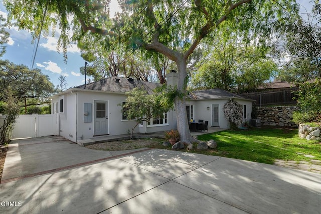 back of house featuring fence, stucco siding, a chimney, a yard, and a patio area