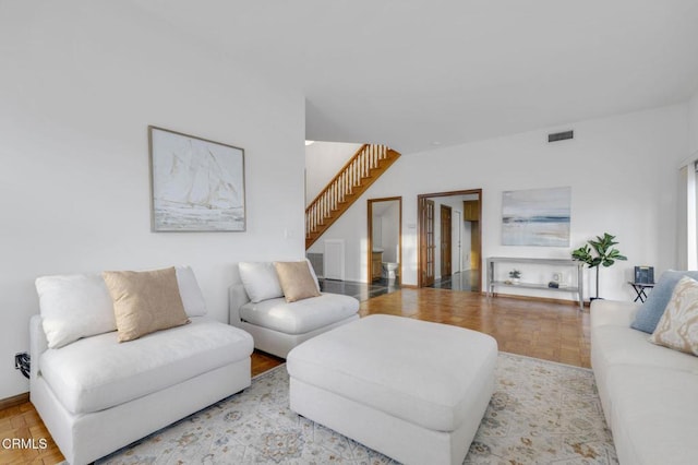 living area featuring visible vents, stairs, and light wood finished floors