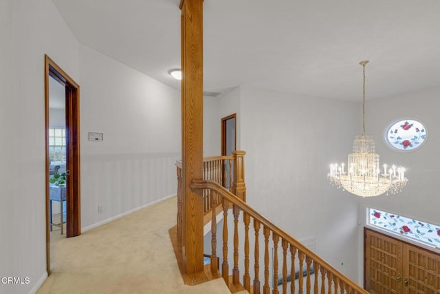 hall with an upstairs landing, carpet flooring, baseboards, and an inviting chandelier