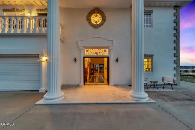 view of exterior entry with stucco siding and a garage