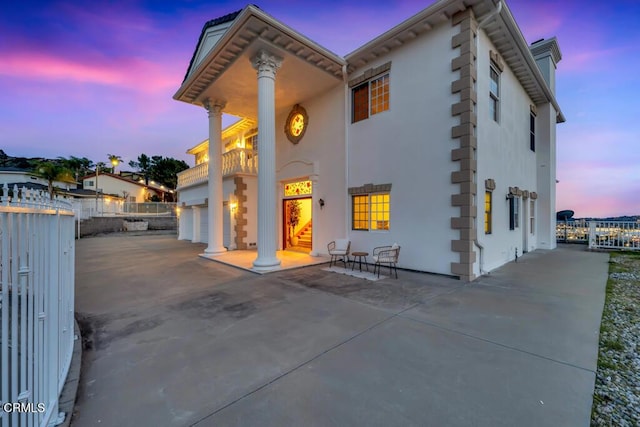 view of front of property featuring a balcony, an attached garage, fence, and stucco siding