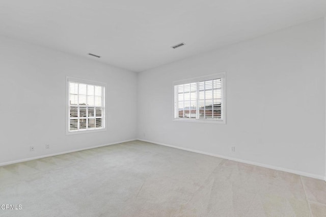 carpeted empty room featuring visible vents and baseboards