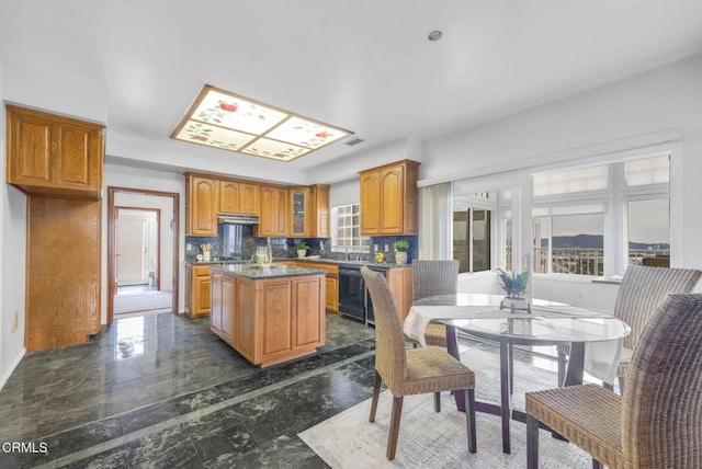 kitchen featuring brown cabinetry, a kitchen island, glass insert cabinets, under cabinet range hood, and dishwasher