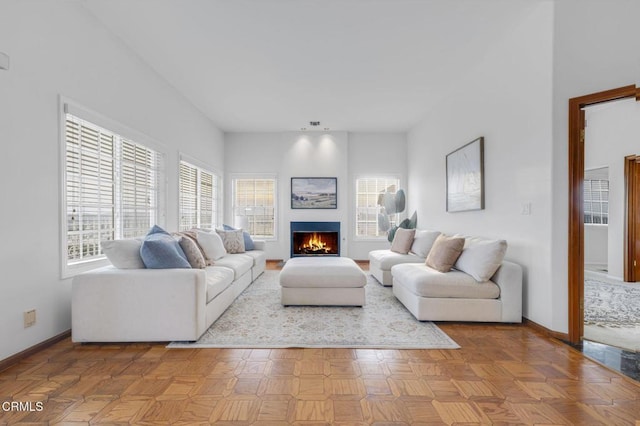 living room with baseboards and a lit fireplace